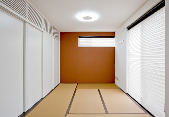 白い引き戸・壁・天井が、朱色の壁をより鮮やかに見せる和室