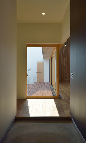 木製サッシから見える、中庭用ドアが立体感を感じる玄関