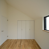 急勾配の屋根面と窓、収納扉の配置が美しい寝室