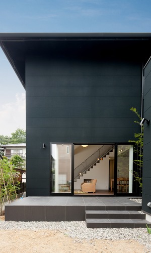 黒い面積が多い外壁から伸びるように広がる中庭