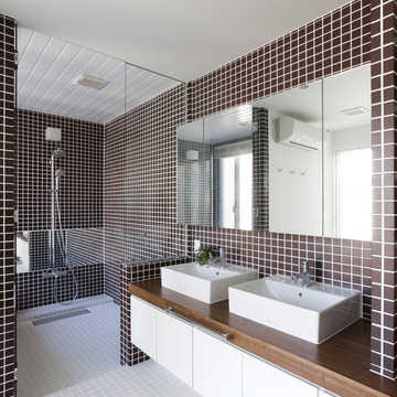浴室との仕切りガラスが空間に狭さを感じさせない、茶色のタイルが印象的な洗面所