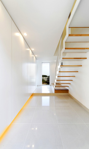 白でまとめたシンプルな玄関ホールに、足元をふんわりと照らす間接照明