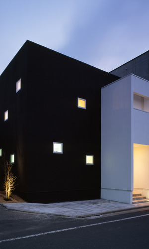黒と白でできた建物にガラスタイルのように眩い光を放つ、夕方の外観
