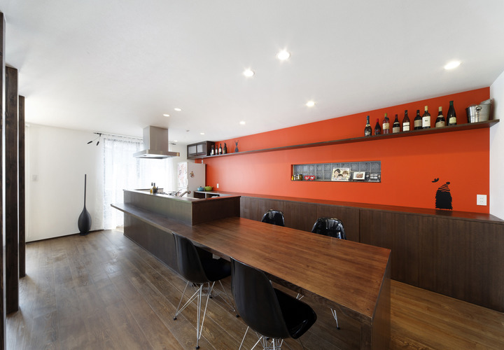 食欲を増す朱色の壁面が、焦げ茶色でまとめた空間にインパクトを与えるキッチン