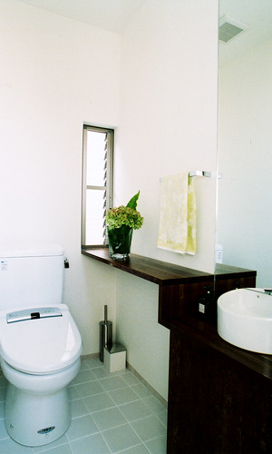 手洗い場と棚を造形的に一つにまとめた、明るい光が入るトイレ