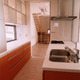 差し色のオレンジ色と、床タイルがよく似合う収納力のあるキッチン