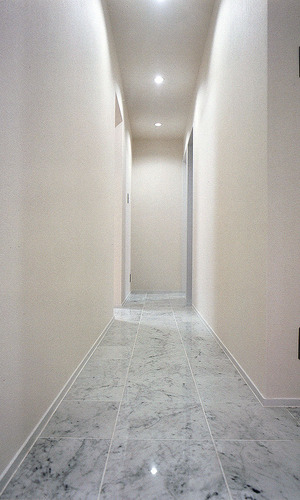 床を大理石調タイルでまとめた、シックでクールな印象の廊下