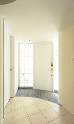 ガラスブロックに包まれた玄関ホールとシンプルモダンなデザインの玄関ドア