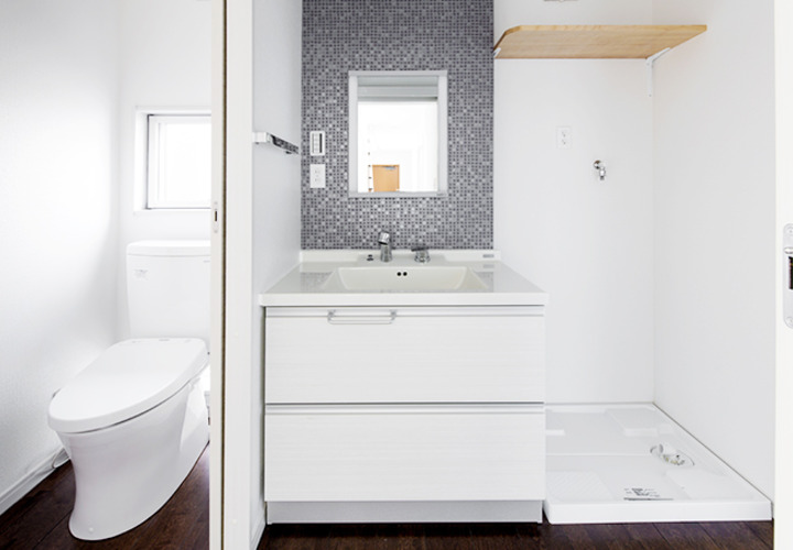 白い空間にグレーのタイルがモダンな雰囲気を醸し出す洗面・トイレ