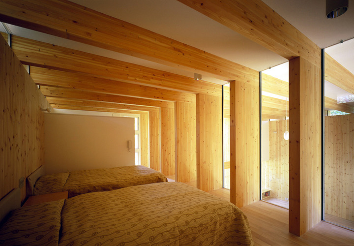 木の梁と自然光で包まれた寝室。日常から離れて自然を楽しむ
