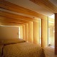 木の梁と自然光で包まれた寝室。日常から離れて自然を楽しむ
