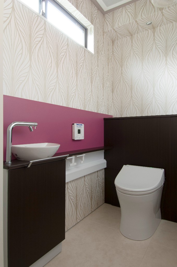 鮮やかなピンクと有機的な柄がモダンな壁紙が調和したオシャレなトイレ