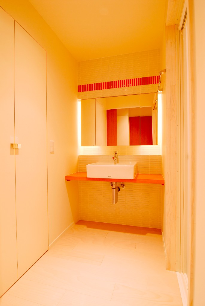 鏡裏の照明と赤いタイルがおしゃれな洗面スペース