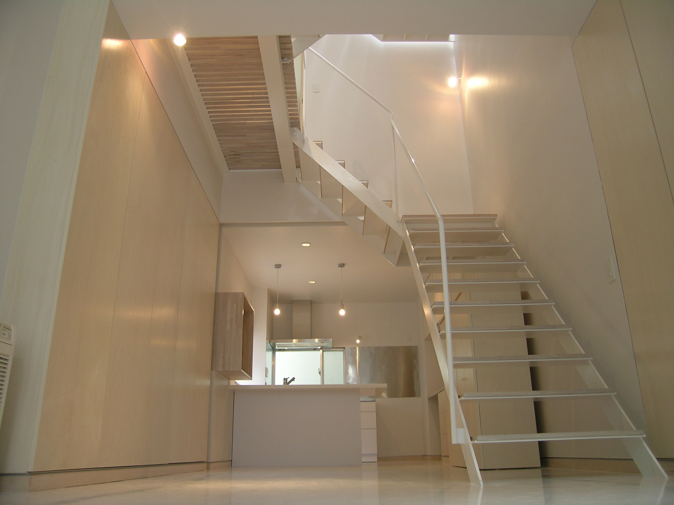 床壁天井の白い空間に建具や階段の踏み板が薄いベージュで優しい雰囲気