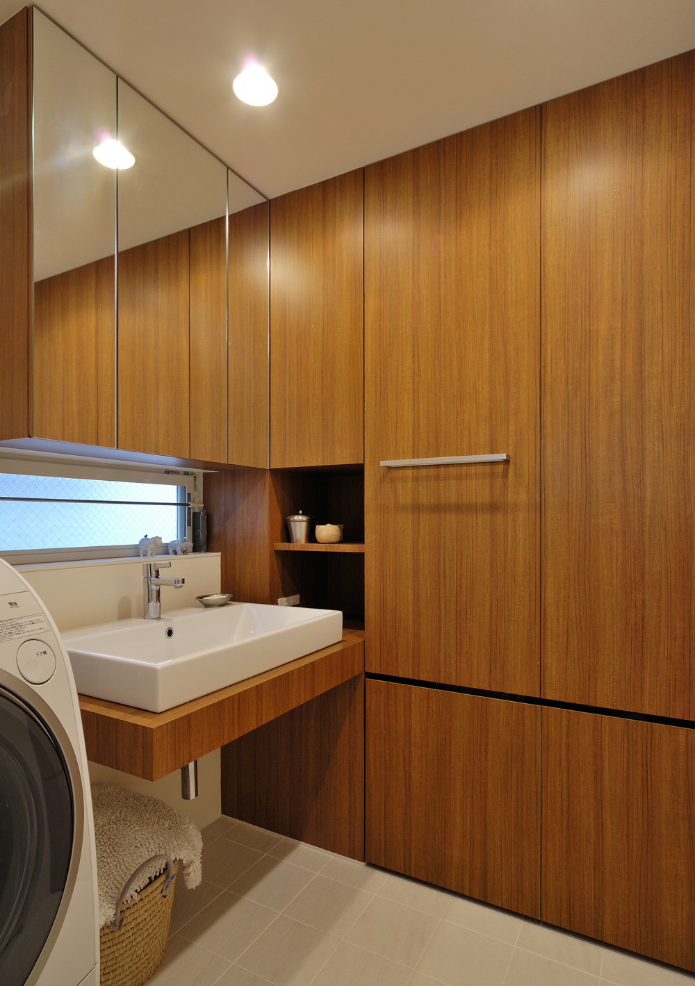 壁一面を洗面カウンターと同素材の木目収納とし、デザイン力と収納力を兼ね添えた洗面所