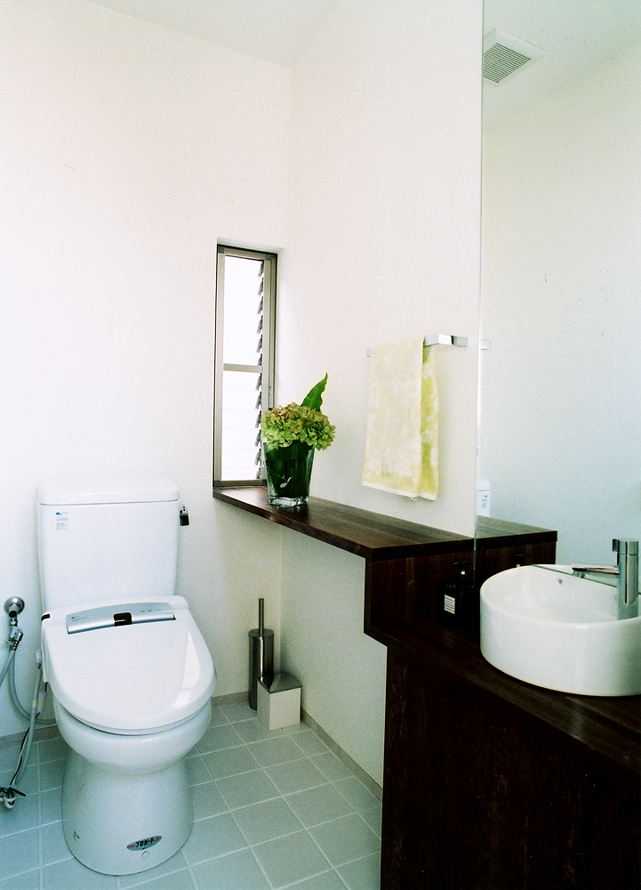 手洗い場と棚を造形的に一つにまとめた、明るい光が入るトイレ