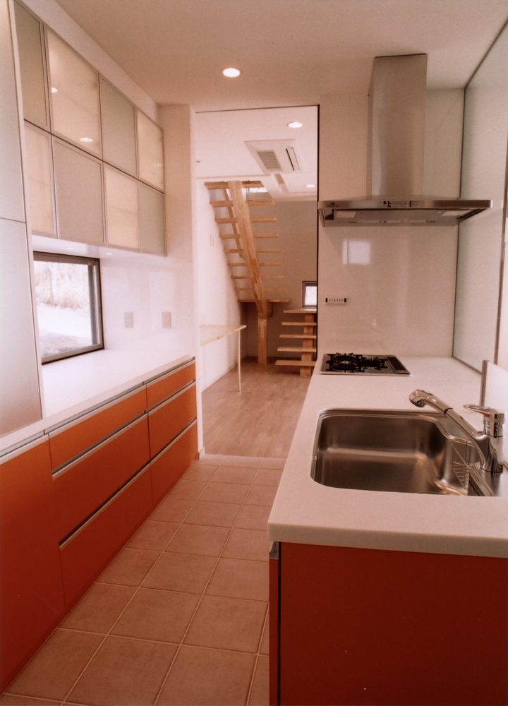 差し色のオレンジ色と、床タイルがよく似合う収納力のあるキッチン