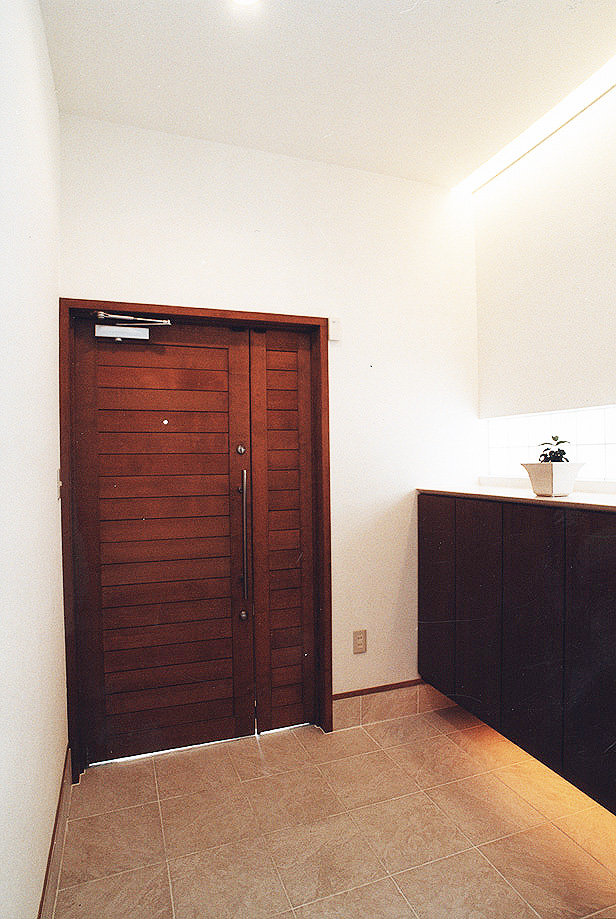 真っ白な壁に、焦げ茶色の木調で仕上げた玄関ドアがポイントのシンプルな玄関