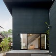 黒い面積が多い外壁から伸びるように広がる中庭