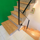 ビビッドなグリーンの壁に調和する階段のナチュラルな踏み板と黒い手すり