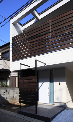 白くシンプルな外壁に木製格子が映えるアプローチ