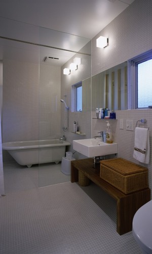 薄いグレーの床壁に白い洗面台や置き浴槽が素敵なバスルーム