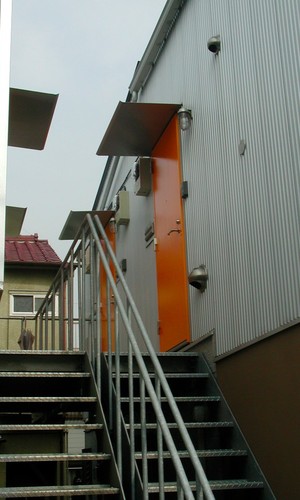 ガルバリウムの外壁に鮮やかなオレンジ色の玄関ドア