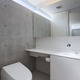 コンクリート打ちっぱなし壁上の高窓から優しい光が入るトイレ