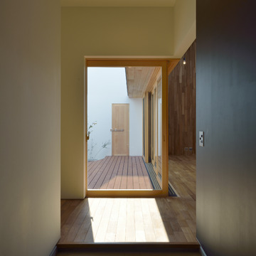 木製サッシから見える、中庭用ドアが立体感を感じる玄関