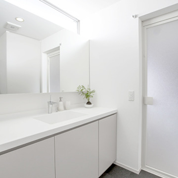高い位置の窓から十分な明るさを確保した白い洗面所