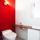 単調になりがちなトイレ空間の、アクセントになる色鮮やかな赤色の壁