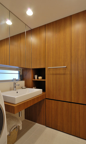 壁一面を洗面カウンターと同素材の木目収納とし、デザイン力と収納力を兼ね添えた洗面所