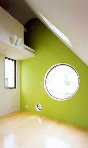 丸い窓とグリーンの壁が印象的な部屋
