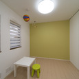 若草色の壁と柔らかい光が入るロールカーテンが印象的な、かわいらしい子供部屋