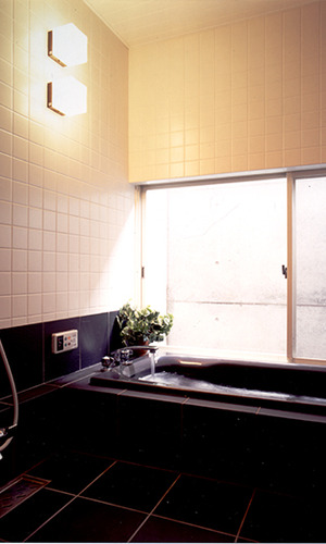 黒のバスタブにコンクリートの壁がシックな浴室