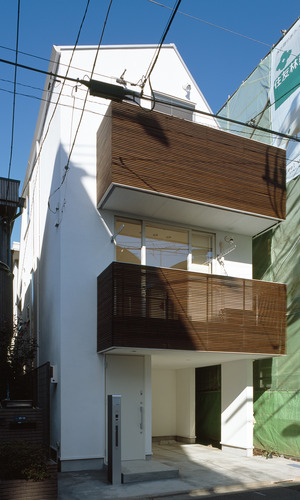 白い外壁と、木目が美しいルーバーが特徴の都市型住宅の外観