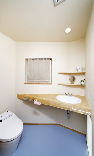 変形型の空間に角を有効活用した、水色の床がかわいらしいトイレ