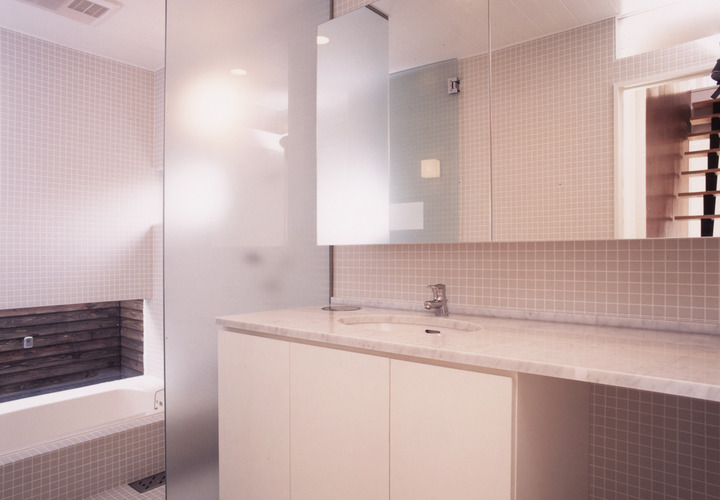 床壁を小さなグレー色のタイルでまとめた、すっきりとした洗面所・浴室