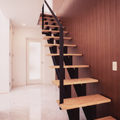 黒と木調でまとめた階段周りを上品にまとめる、階段ホールの白い石調タイル