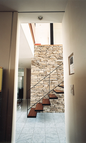 重厚感ある人造石貼の壁と対象的に、浮遊しているような軽やかさを持った階段