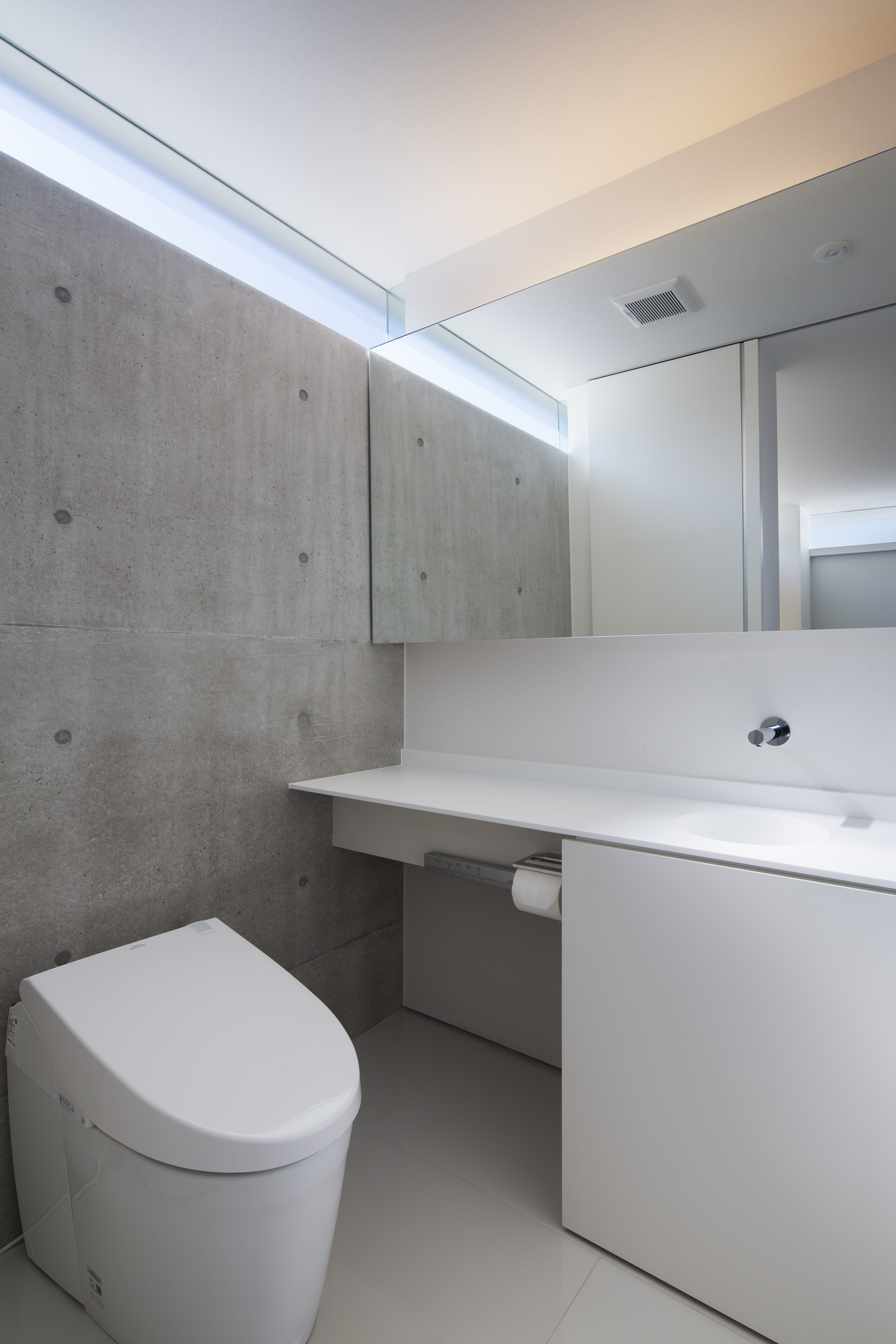 コンクリート打ちっぱなし壁上の高窓から優しい光が入るトイレ