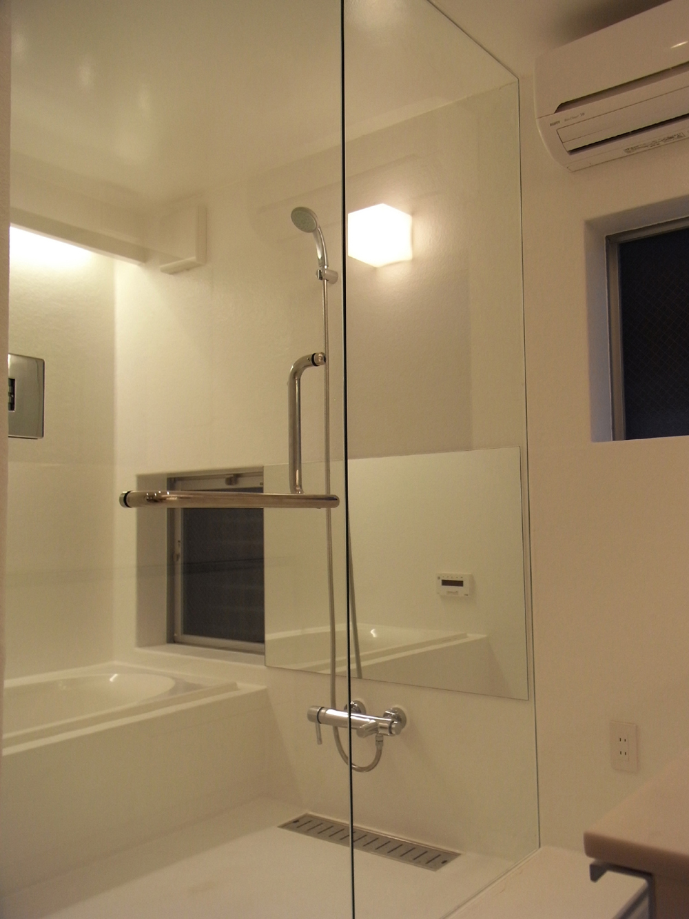 浴室扉と仕切りをガラスにし、洗面ルームと一体化して見えるバスルーム