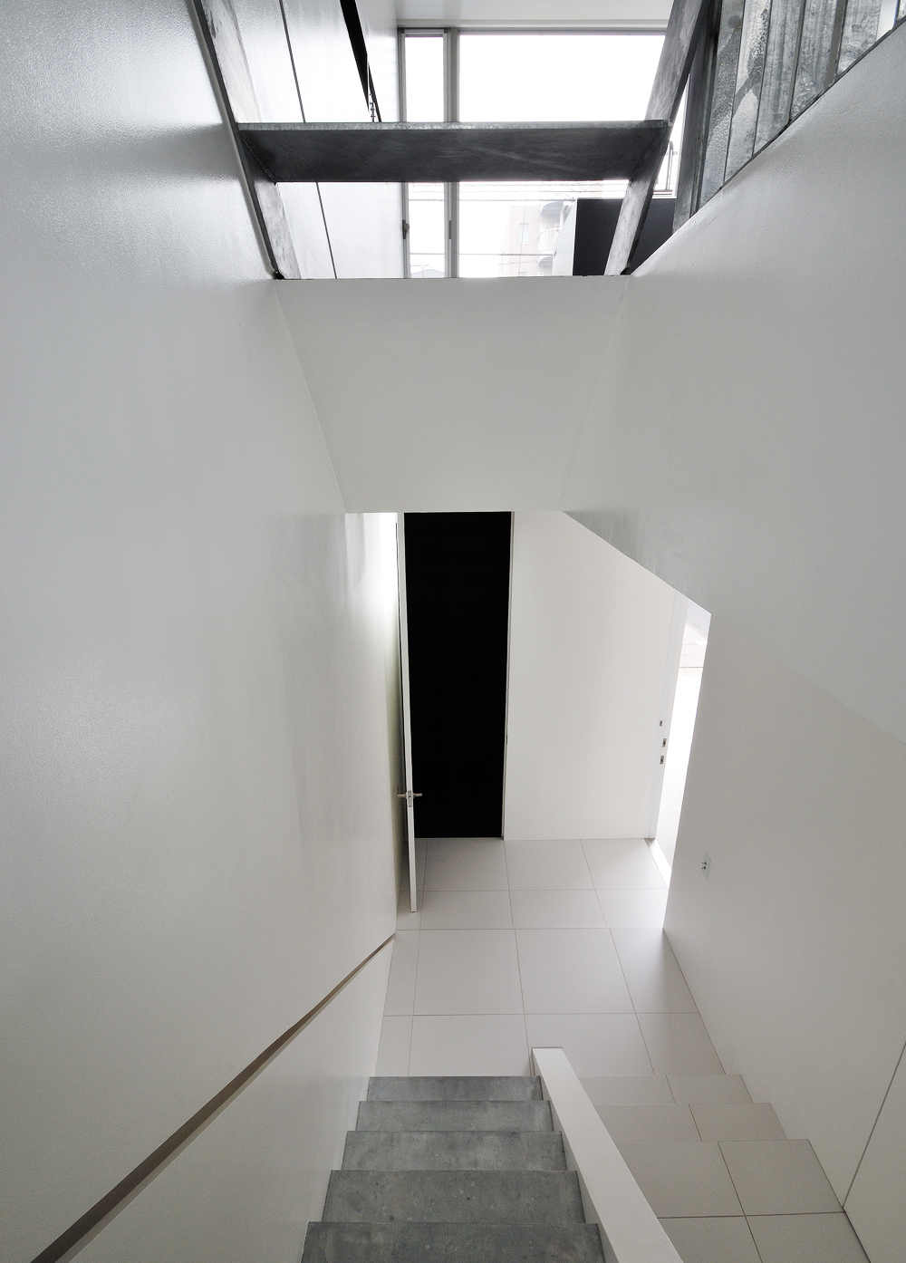 美しい白の床壁と、素材そのものが活かされた階段が新鮮な玄関ホール
