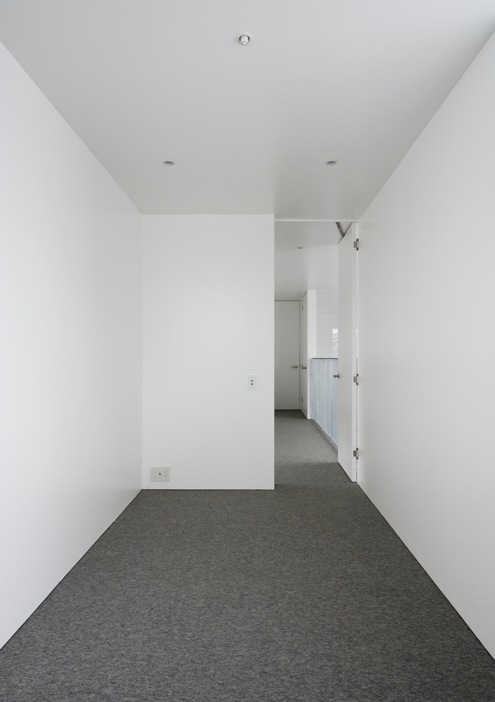 白でまとめた壁・天井がグレーのカーペットを引き立てる洋室