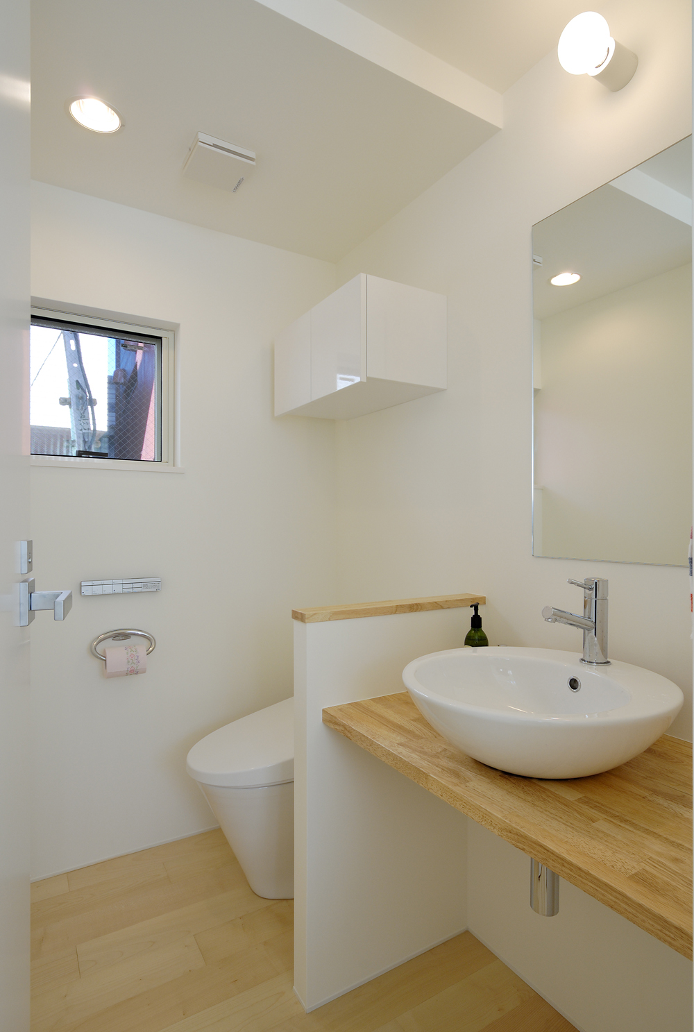 白木と白を基調にした、トイレと洗面所をユニットさせ広さを強調した空間