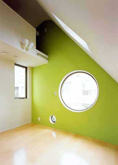 丸い窓とグリーンの壁が印象的な部屋
