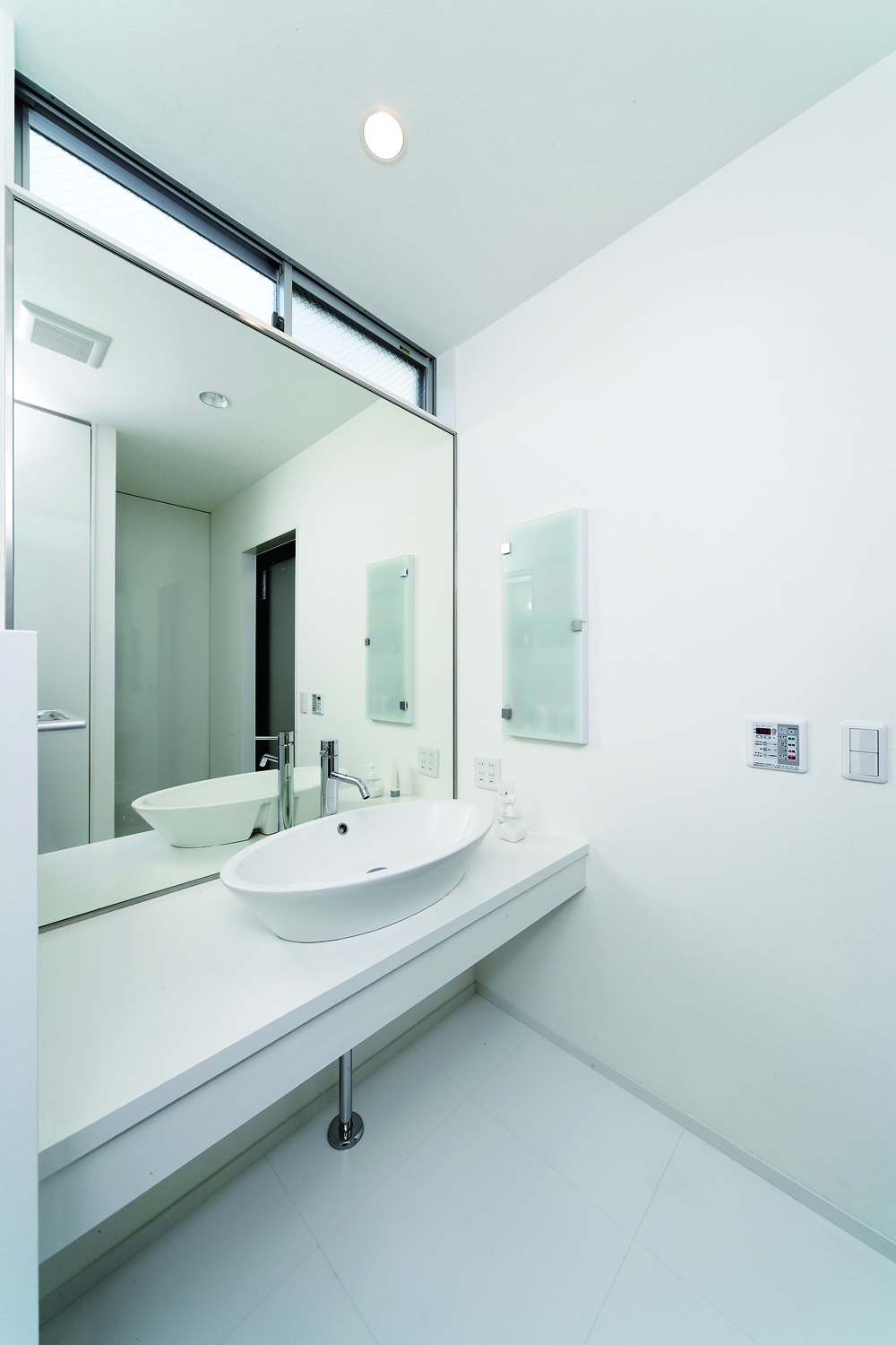 トップライトからの光と壁一面の鏡が、洗面所を広く見せる手段の一つ