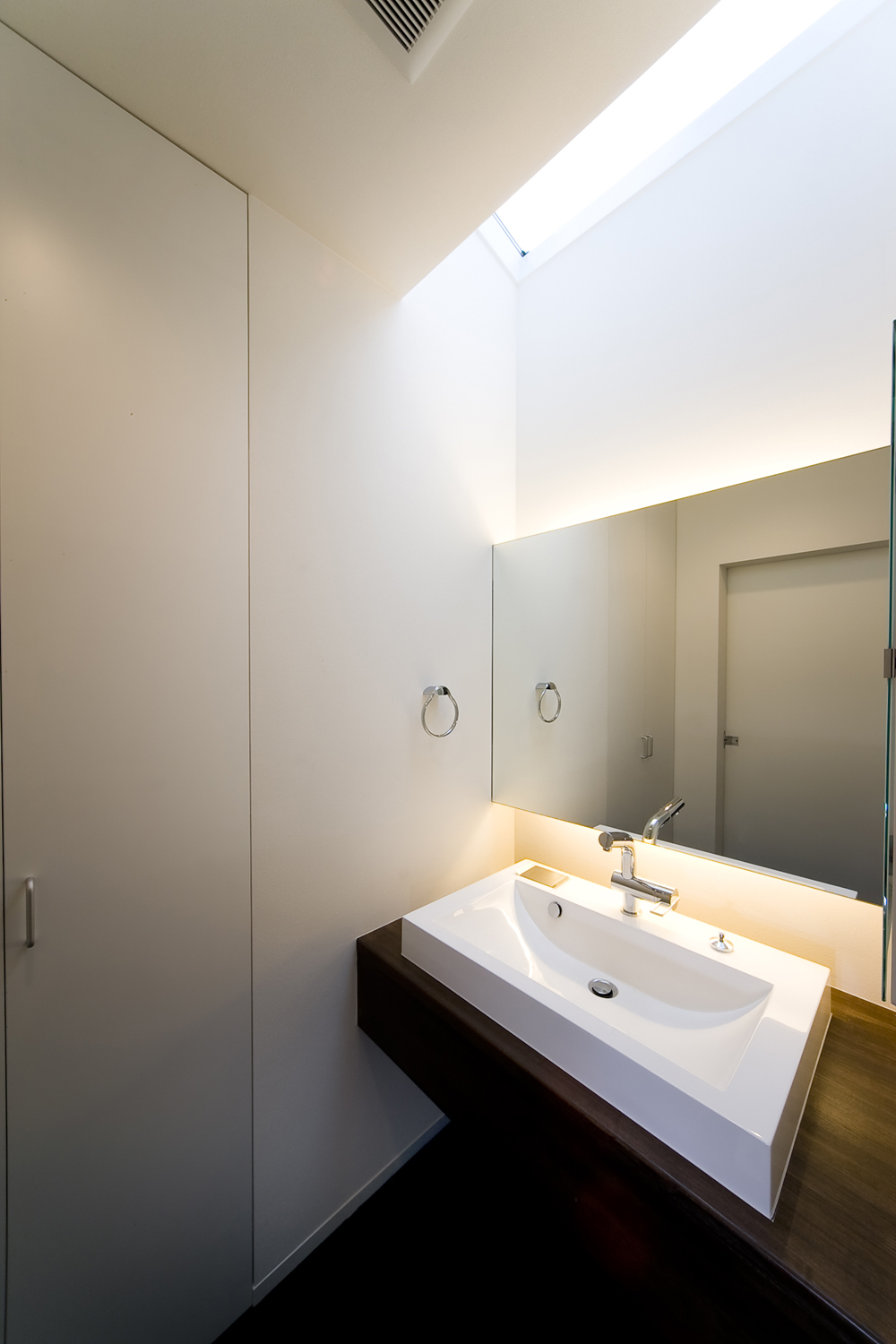 天井からの光、アッパー＆ダウン照明がふんわりとした空気を生むシンプルな洗面所
