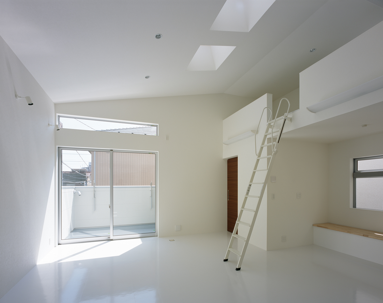 斜め天井より差し込む光が白い床に反射する、のびやかなリビング