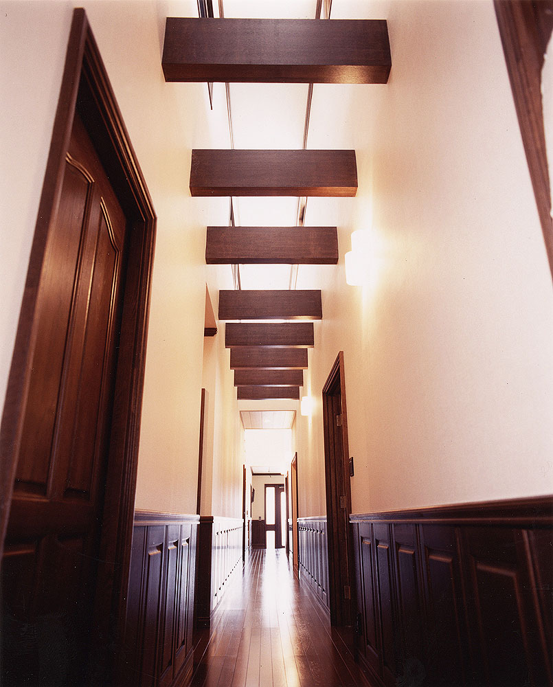吹き抜け空間に梁をデザインに盛り込んだ、腰壁のある奥行きのある廊下